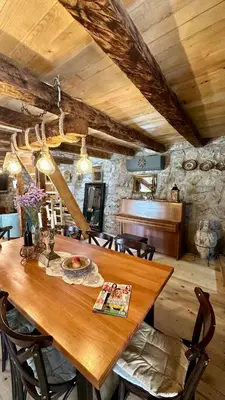 a dining room with a wooden table and a piano at Rustic house Pojata in Njeguši