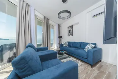 a living room with blue furniture and a large window at Skyline Vista in Becici