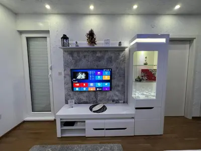 a white entertainment center with a tv on a wall at White Cloud by Rent a Car MI in Podgorica