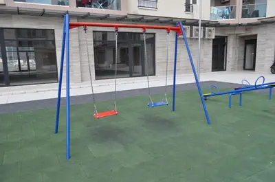 an empty playground with swings in front of a building at White Cloud by Rent a Car MI in Podgorica