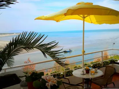 a balcony with a table and an umbrella and the beach at Apartments Kepi Gjerana in Ulcinj