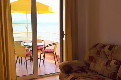 a living room with a chair and a table and a balcony at Apartments Kepi Gjerana in Ulcinj