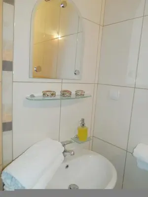 a white bathroom with a sink and a mirror at Apartments Kepi Gjerana in Ulcinj