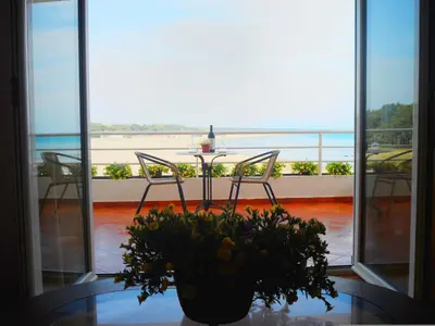 a table and chairs with a vase of flowers on a table at Apartments Kepi Gjerana in Ulcinj