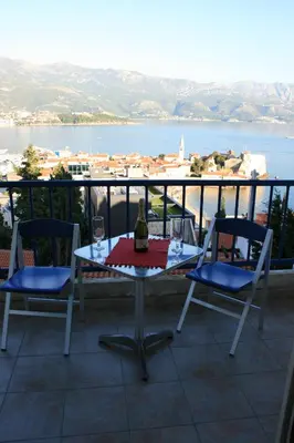 a table with a wine glass and two chairs on a balcony at Belvedere Apartments in Budva