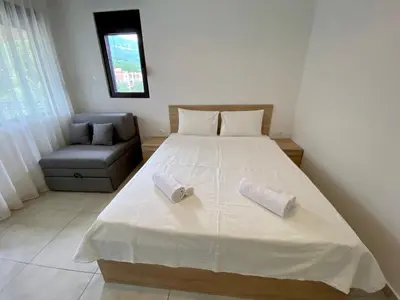 a bedroom with a large white bed and a chair at Villa Dolphin Apartments in Petrovac na Moru