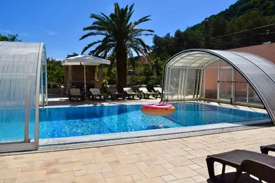 a swimming pool with a tent and a pool noodle in the water at Villa Dolphin Apartments in Petrovac na Moru
