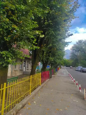 a yellow fence next to a road with trees at Center 1 Podgorica in Podgorica