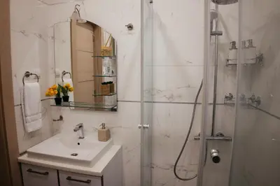 a white bathroom with a sink and a shower at Luxury Apartment Budva in Budva