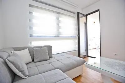 a living room with a couch and a large window at Lux Stanovi Vucetic in Bar