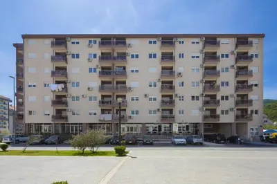a large apartment building with cars parked in a parking lot at Apartment Ana in Budva