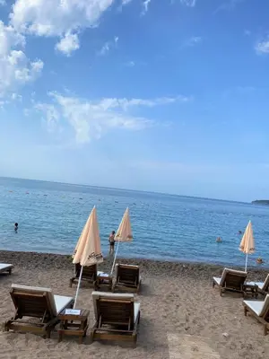 a group of lounge chairs and umbrellas on a beach at MonteRelax Apartments Becici in Rafailovici