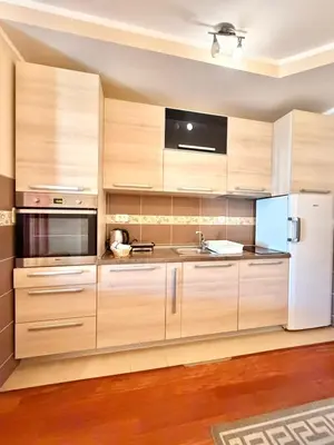 a kitchen with wooden cabinets and a white refrigerator at Beachfront Apartments Oaza 2 in Petrovac na Moru