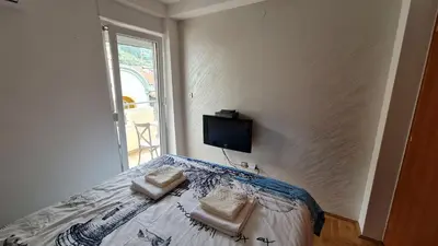 a bedroom with a bed with a tv on the wall at Apartman Elijana in Budva
