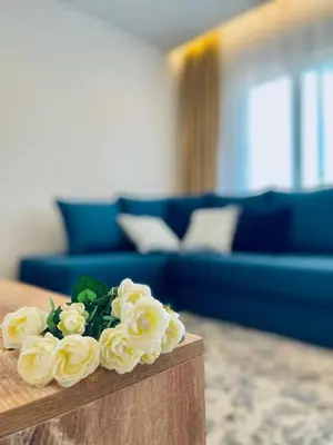 a living room with a blue couch and flowers on a table at Garden Villas in Donji Štoj