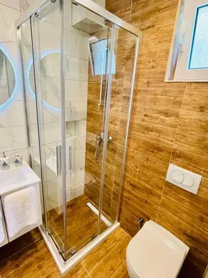 a bathroom with a shower and a toilet and a sink at Garden Villas in Donji Štoj