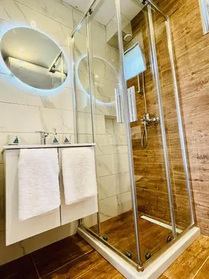 a shower in a bathroom with white towels at Garden Villas in Donji Štoj