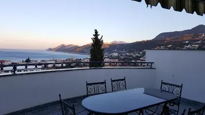 a table and chairs on a balcony with a view of the ocean at Villa M in Dobra Voda