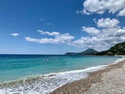 a beach with blue water and a rocky shoreline at Corall apartment Bar in Bar