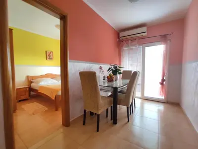 a dining room with a table and a bedroom at Apartmani Tomić 4* in Rafailovici