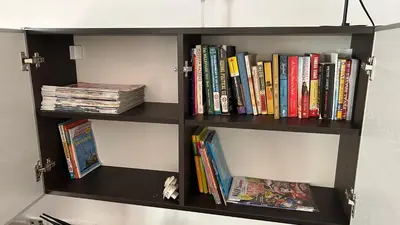a black book shelf filled with books at Apartman Luka Budva in Budva