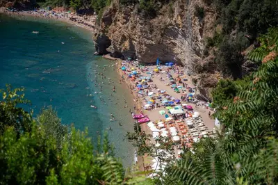 a beach with people and umbrellas and the water at Sunny three-bedroom apartment in Budva in Budva