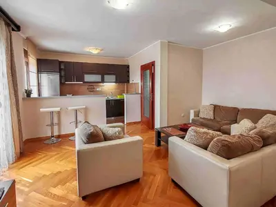 a living room with two couches and a kitchen at Sunny three-bedroom apartment in Budva in Budva