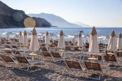 a group of chairs and umbrellas on a beach at Sunny three-bedroom apartment in Budva in Budva