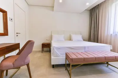 a bedroom with a large white bed and a chair at Sunraf Luxe Apartments in Budva
