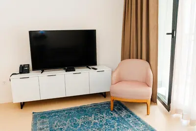 a living room with a flat screen tv and a chair at Sunraf Luxe Apartments in Budva