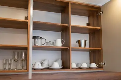 a wooden cabinet with dishes and cups and utensils at Sunraf Luxe Apartments in Budva