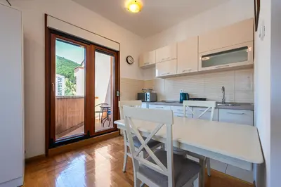 a kitchen with a table and chairs and a window at Cozy studio with terrace in Budva