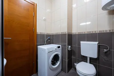 a bathroom with a washing machine and a toilet at Cozy studio with terrace in Budva