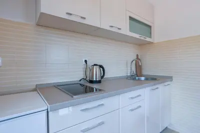 a kitchen with white cabinets and a sink at Cozy studio with terrace in Budva