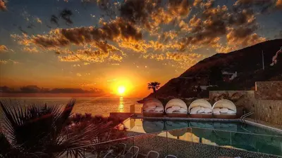 a swimming pool with a sunset in the background at Apartment Your Home in Dobra Voda