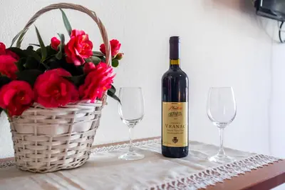 a bottle of wine next to a basket of flowers at Villa Savovic in Petrovac na Moru