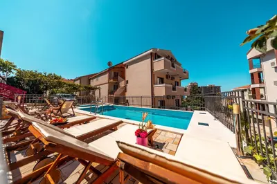 a swimming pool with a bunch of chairs next to a building at Villa Savovic in Petrovac na Moru