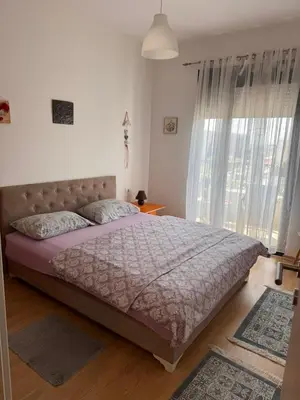 a bedroom with a bed and a large window at Flower and Love Flat Next to centar of podgorica in Podgorica