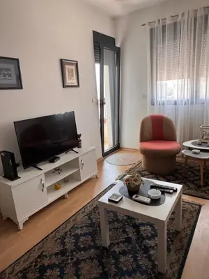 a living room with a flat screen tv and a table at Flower and Love Flat Next to centar of podgorica in Podgorica