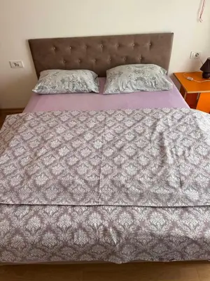a bed with a blanket and pillows on it at Flower and Love Flat Next to centar of podgorica in Podgorica