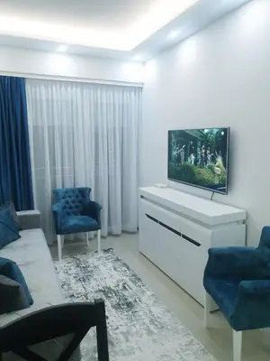 a living room with a tv and blue chairs at LUX Apartment - Central Place Bar in Bar