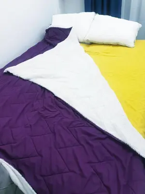 a bed with a purple and white blanket on it at LUX Apartment - Central Place Bar in Bar