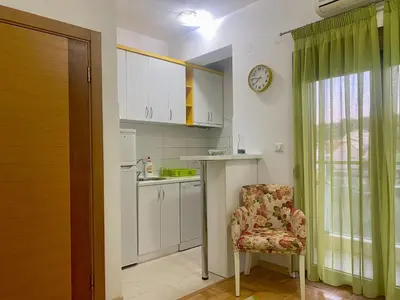 a kitchen with a chair and a table and a clock at RIO 2 in Podgorica