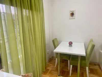 a dining room with a table and green curtains at RIO 2 in Podgorica