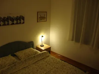 a bedroom with a bed and a lamp on a night stand at Centre Point Apartment in Podgorica