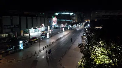 a city street at night with people walking down the street at Centre Point Apartment in Podgorica