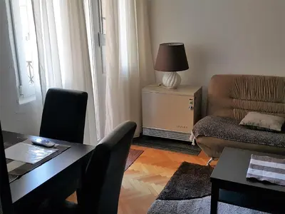 a living room with a table and a chair and a couch at Centre Point Apartment in Podgorica