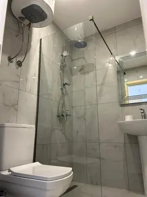 a bathroom with a shower and a toilet and a sink at Apart Hotel White Pearl in Bar