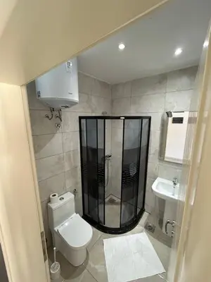 a bathroom with a shower and a toilet and a sink at Apart Hotel White Pearl in Bar