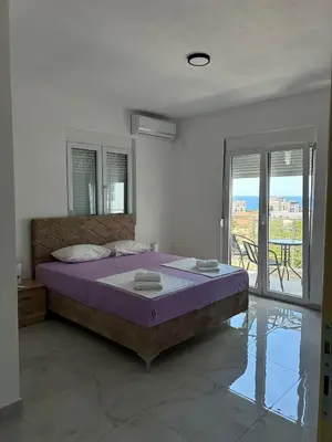 a bedroom with a bed with purple sheets and a balcony at Apart Hotel White Pearl in Bar